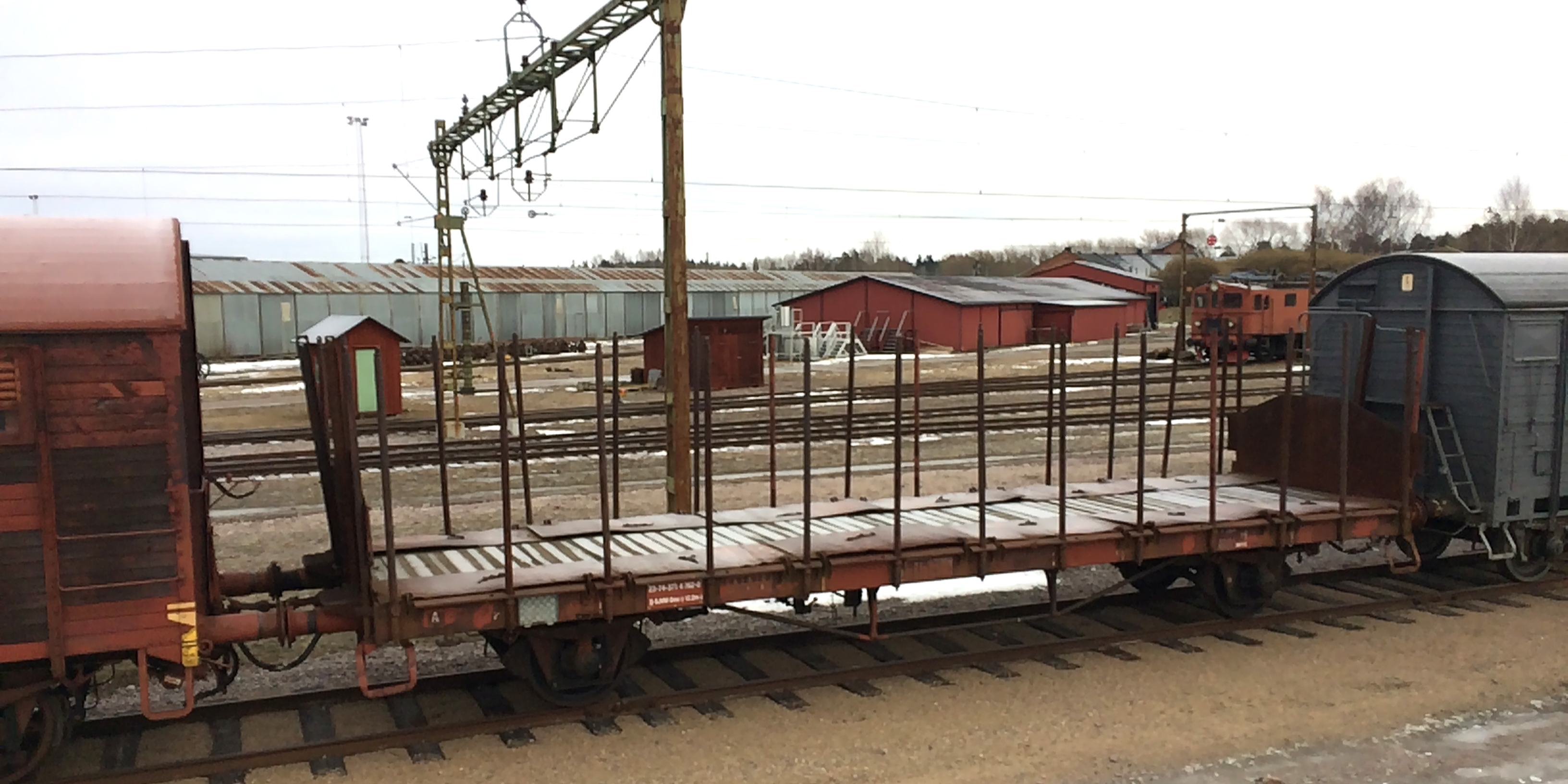 A stationary open rust brown freight wagon on a large track area.