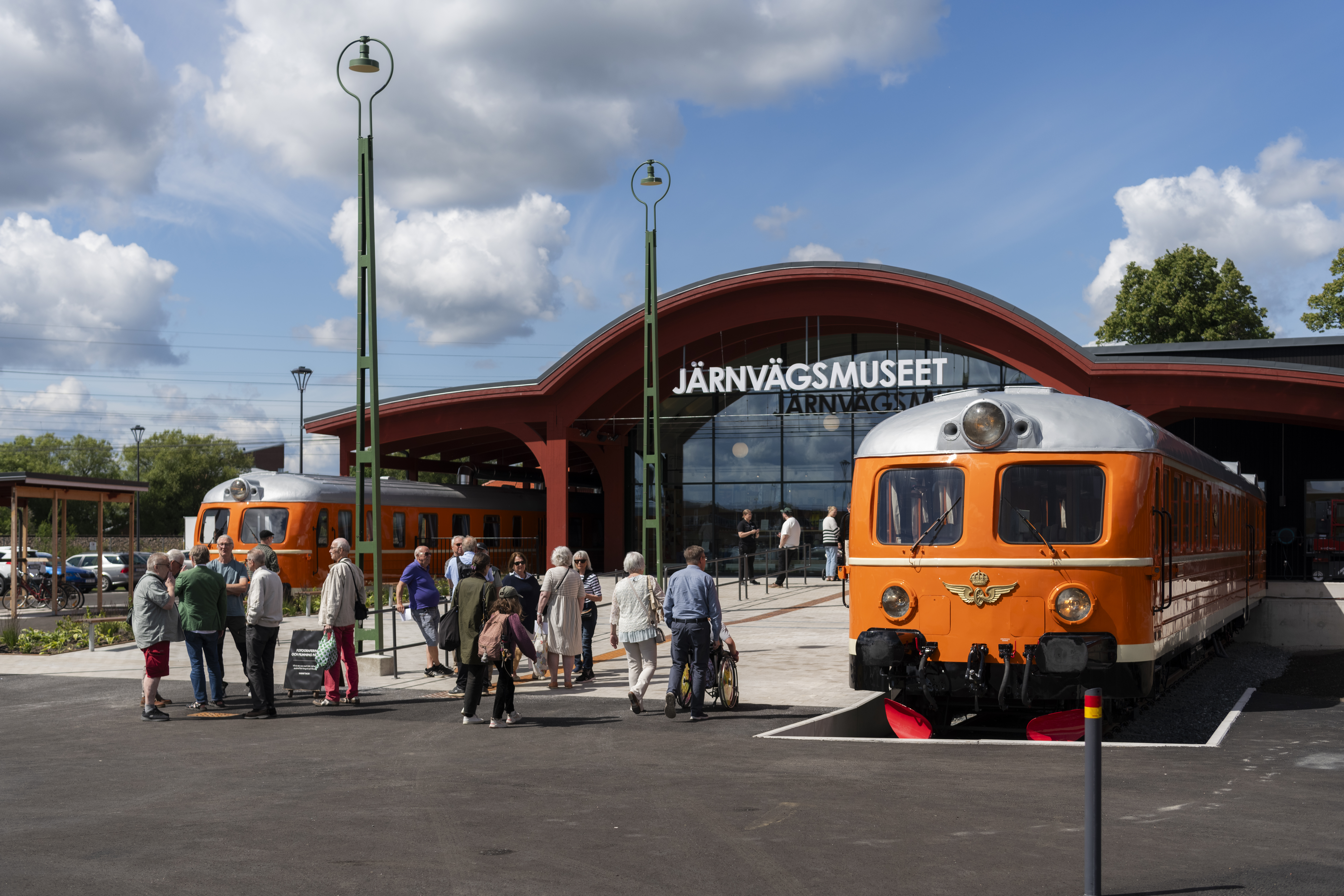 The main entrence to the museum. Two orange train cars frames the entrance. A group of people are about to enter.