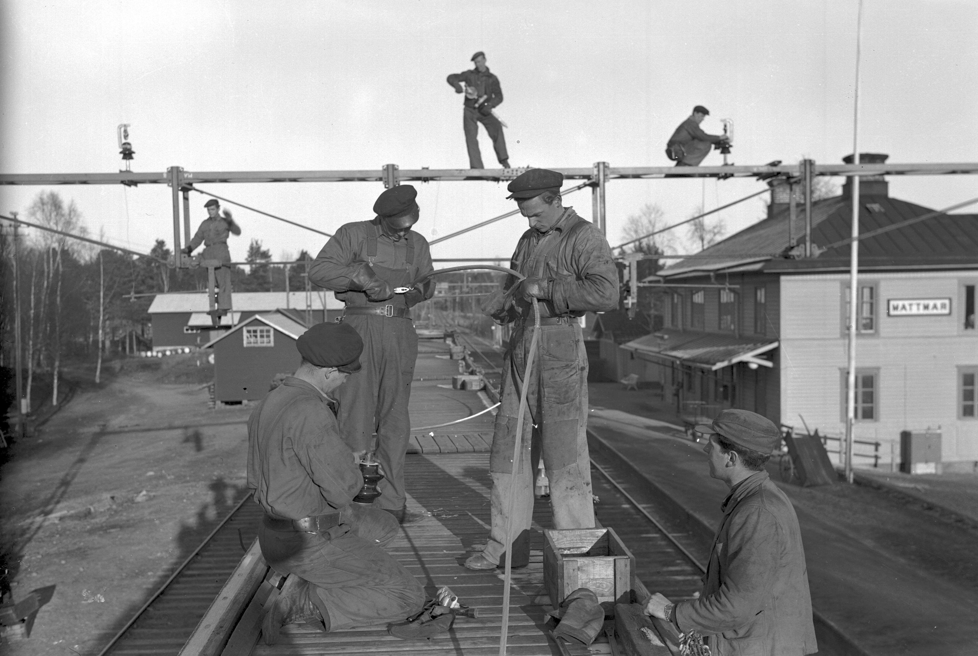 Svartvitt foto från 1945 av män ovanpå en tågvagn och arbetar med ledningar.