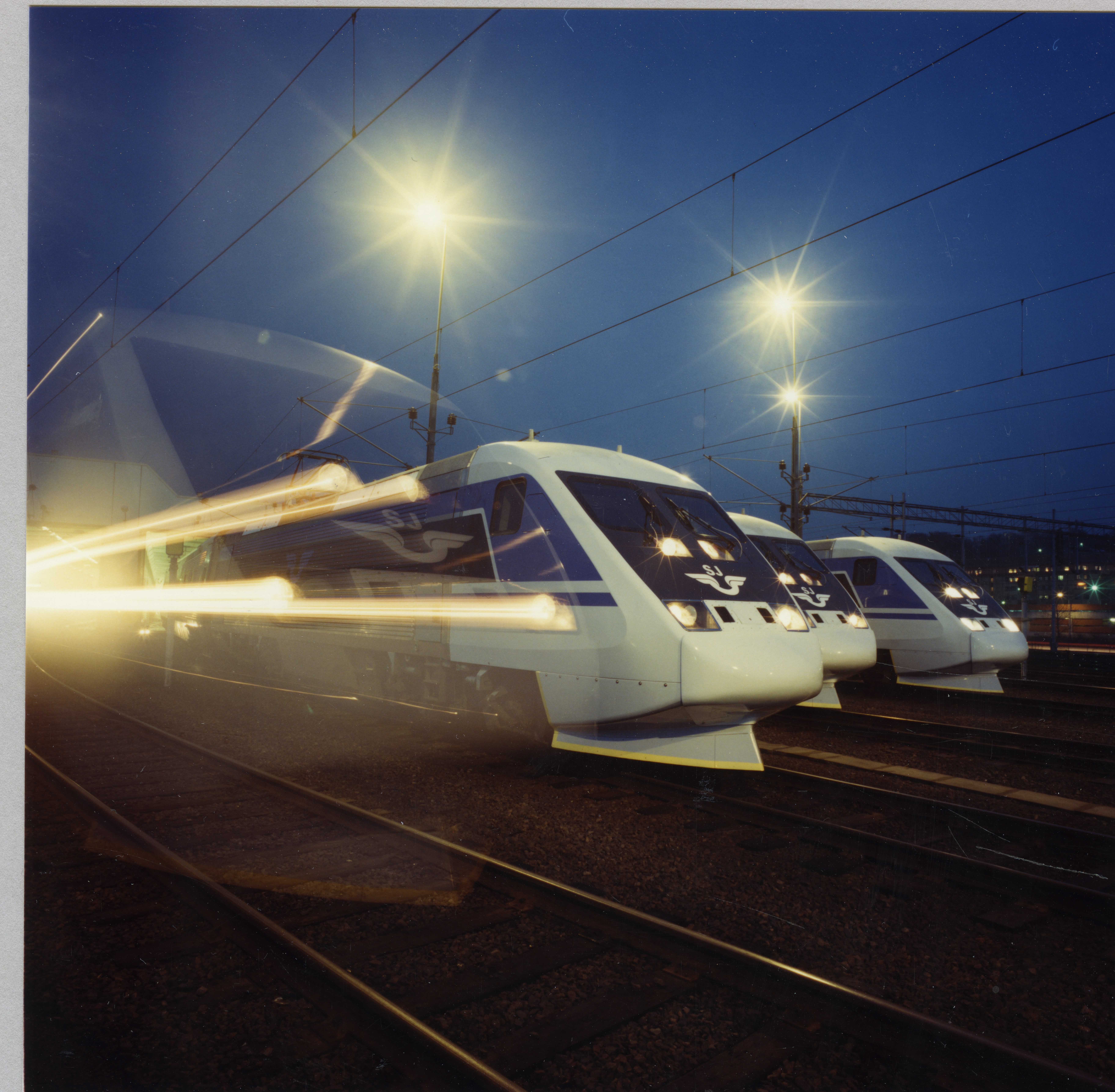Locomotives in line, evening, shining lights and longer shutter speeds that give speed strokes in the picture.