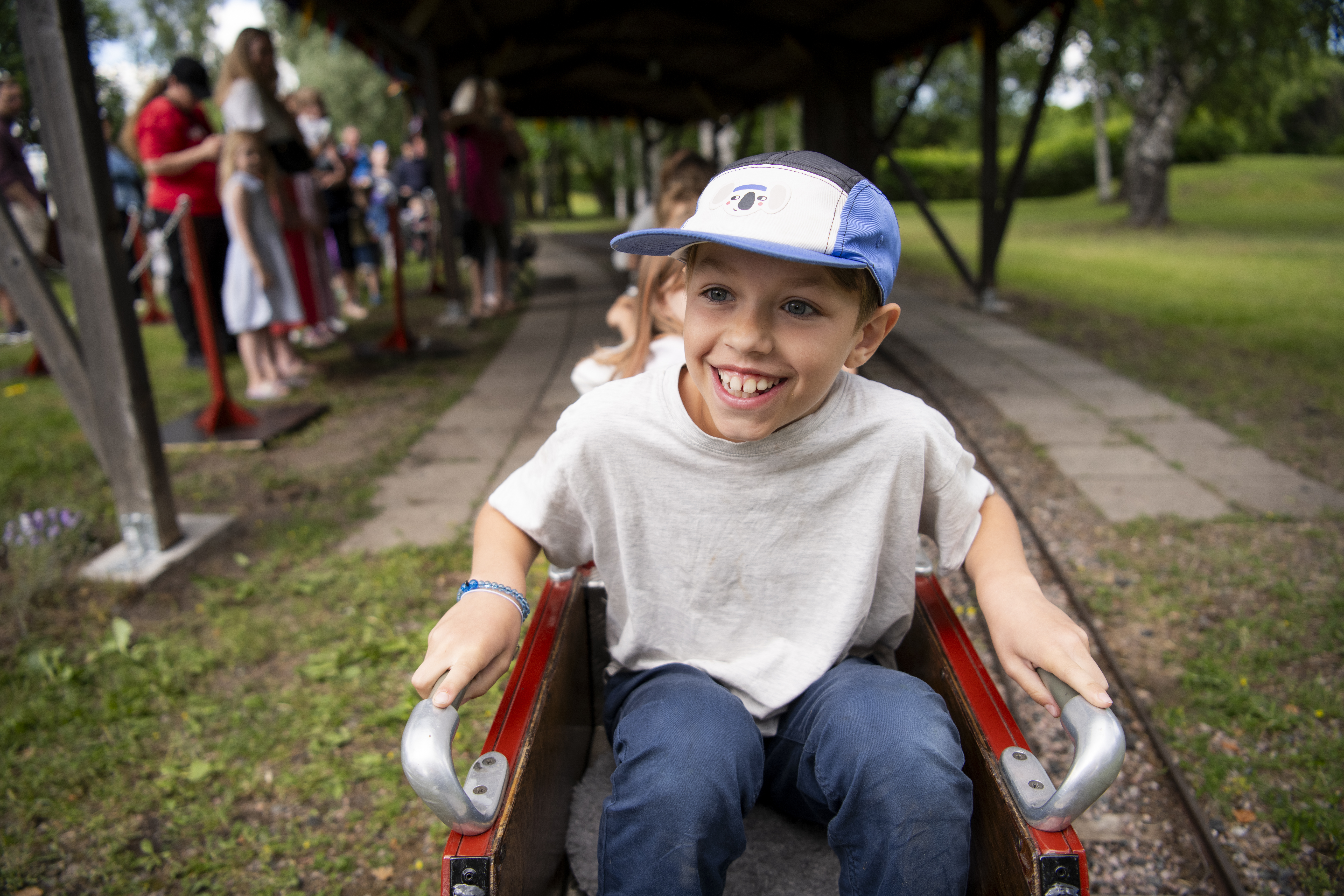 En pojke sitter i ett minitåg och ser glad ut