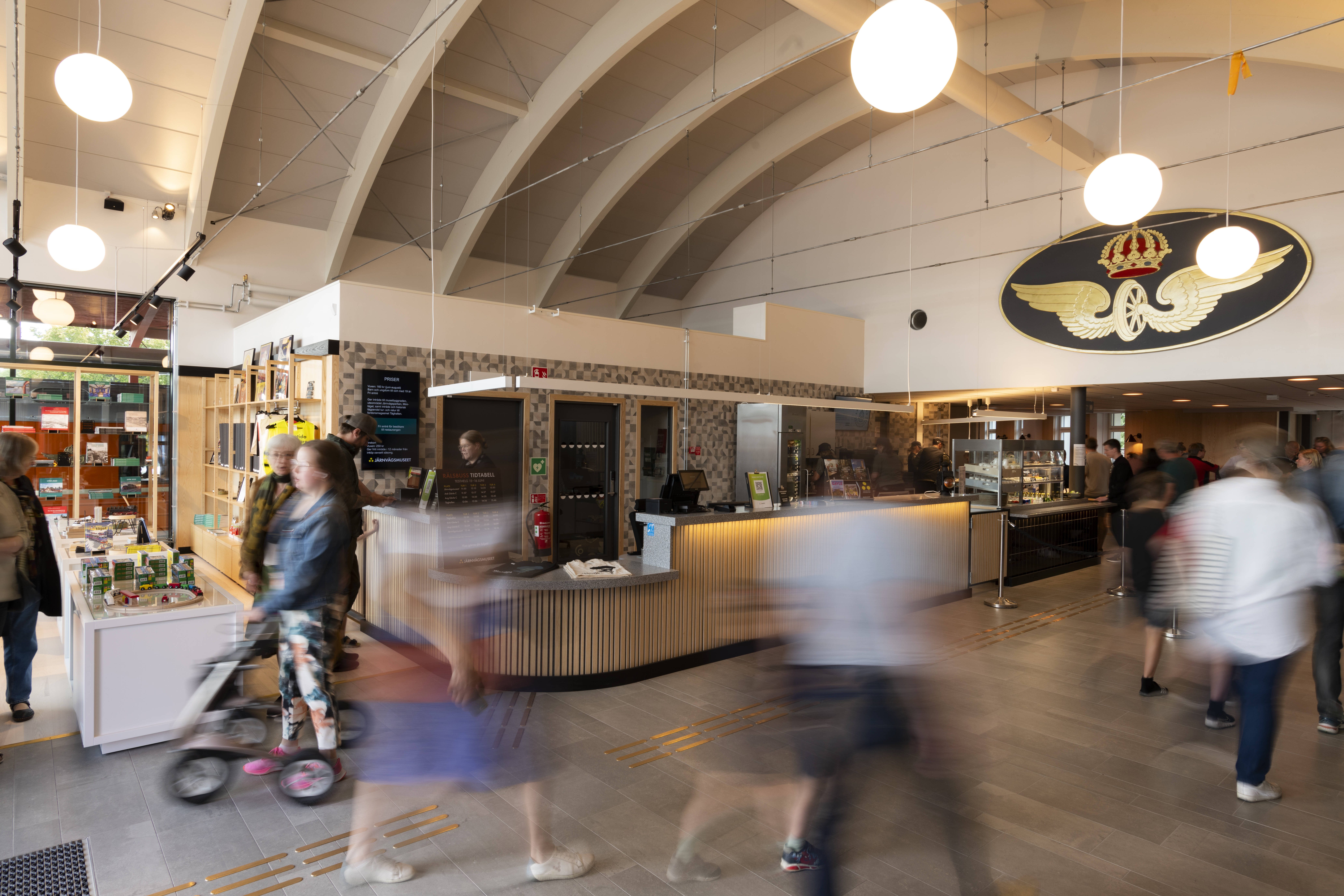 Many people are in movement at the museums entrance. In the background you can see the shop with beautiful objects for sale.