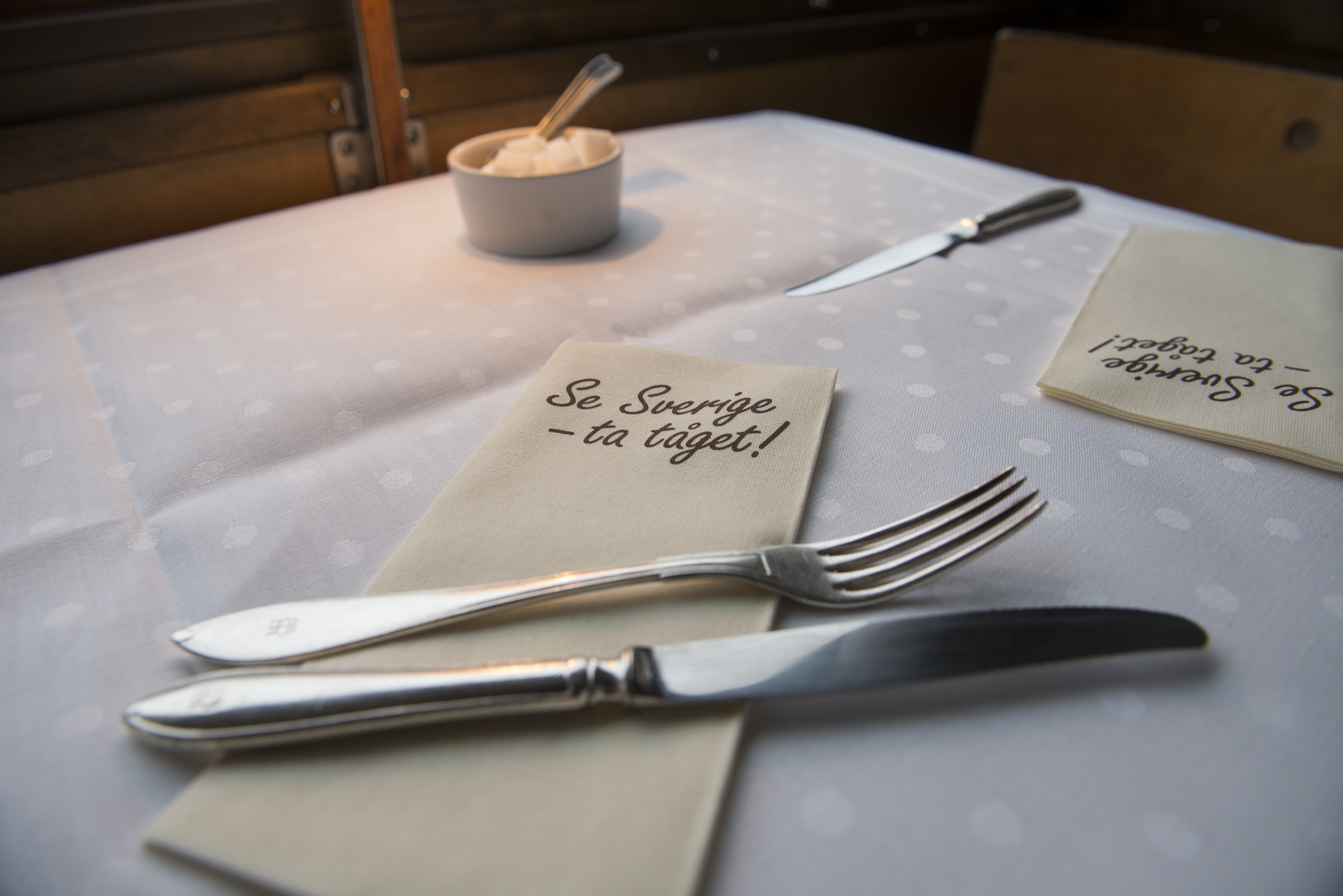 Närbild på ett dukat bord med en servett där det står "se Sverige - ta tåget!"