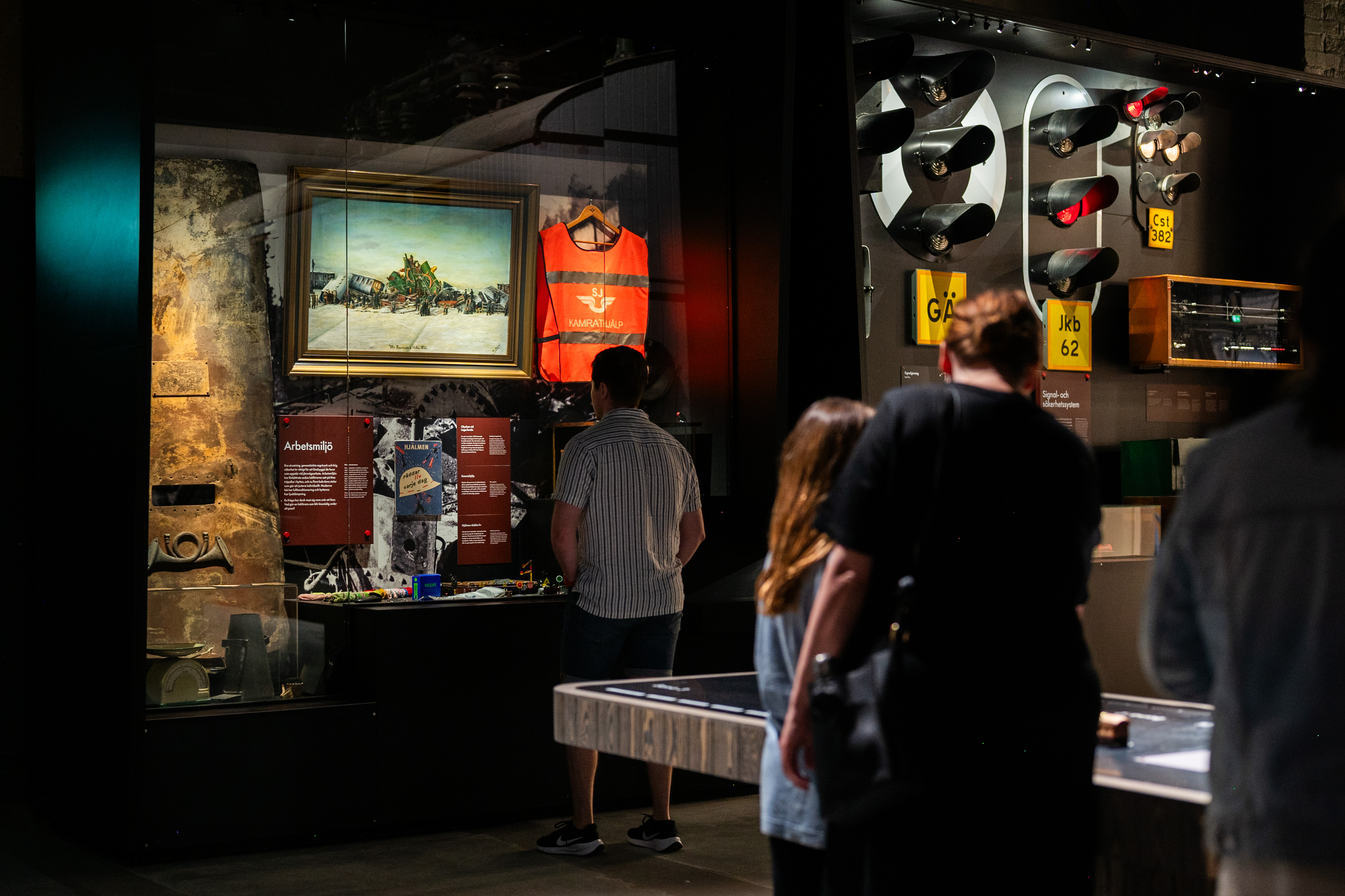 a family is standing in a dark exhibition hall and in front of them you can see lit up displays