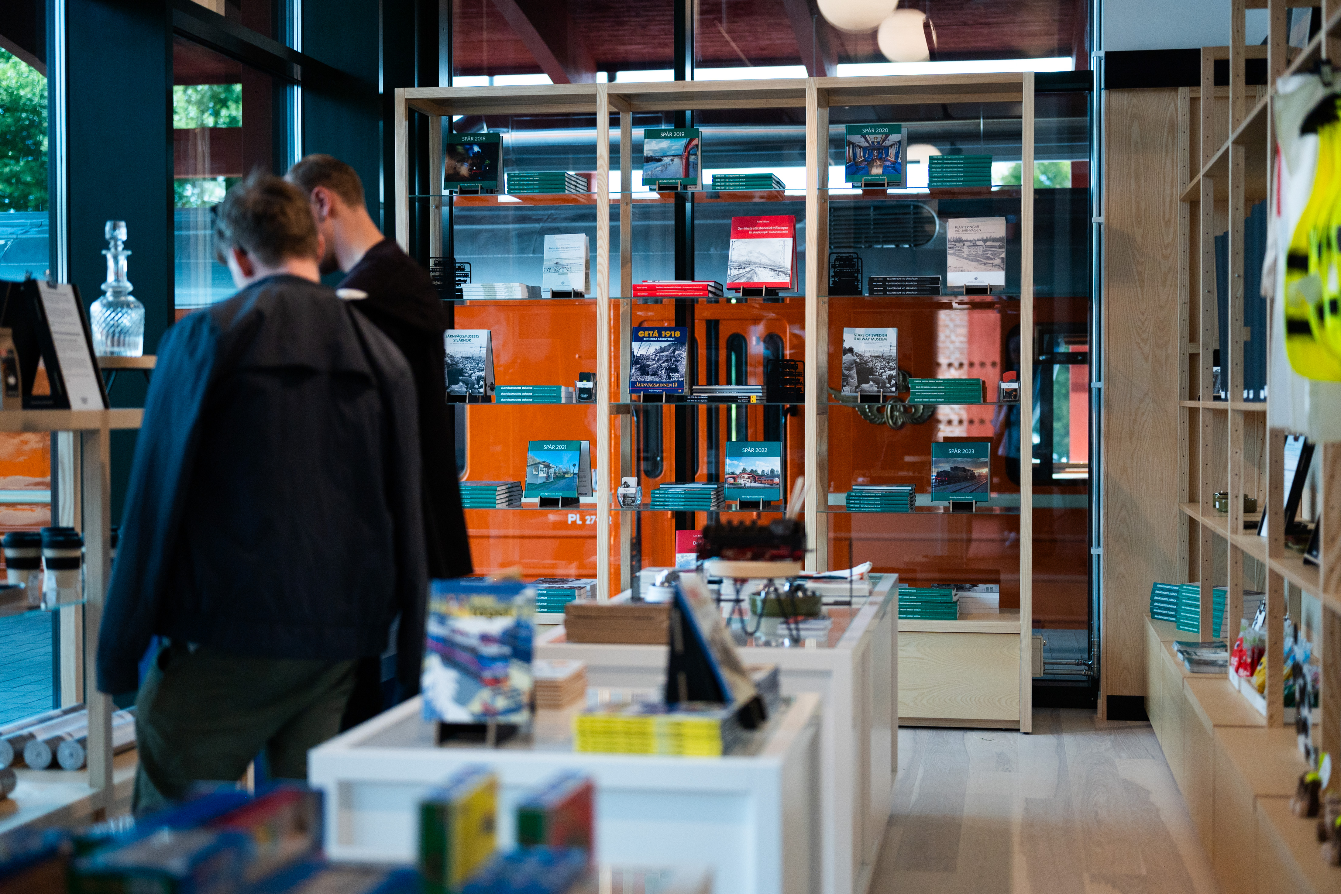 Two male customers are looking at items in small shop.