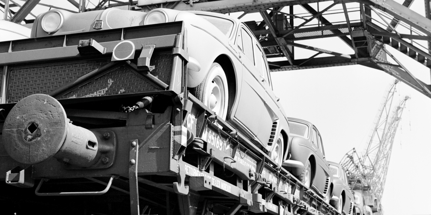 Close-up of open train carriage with passenger cars loaded.