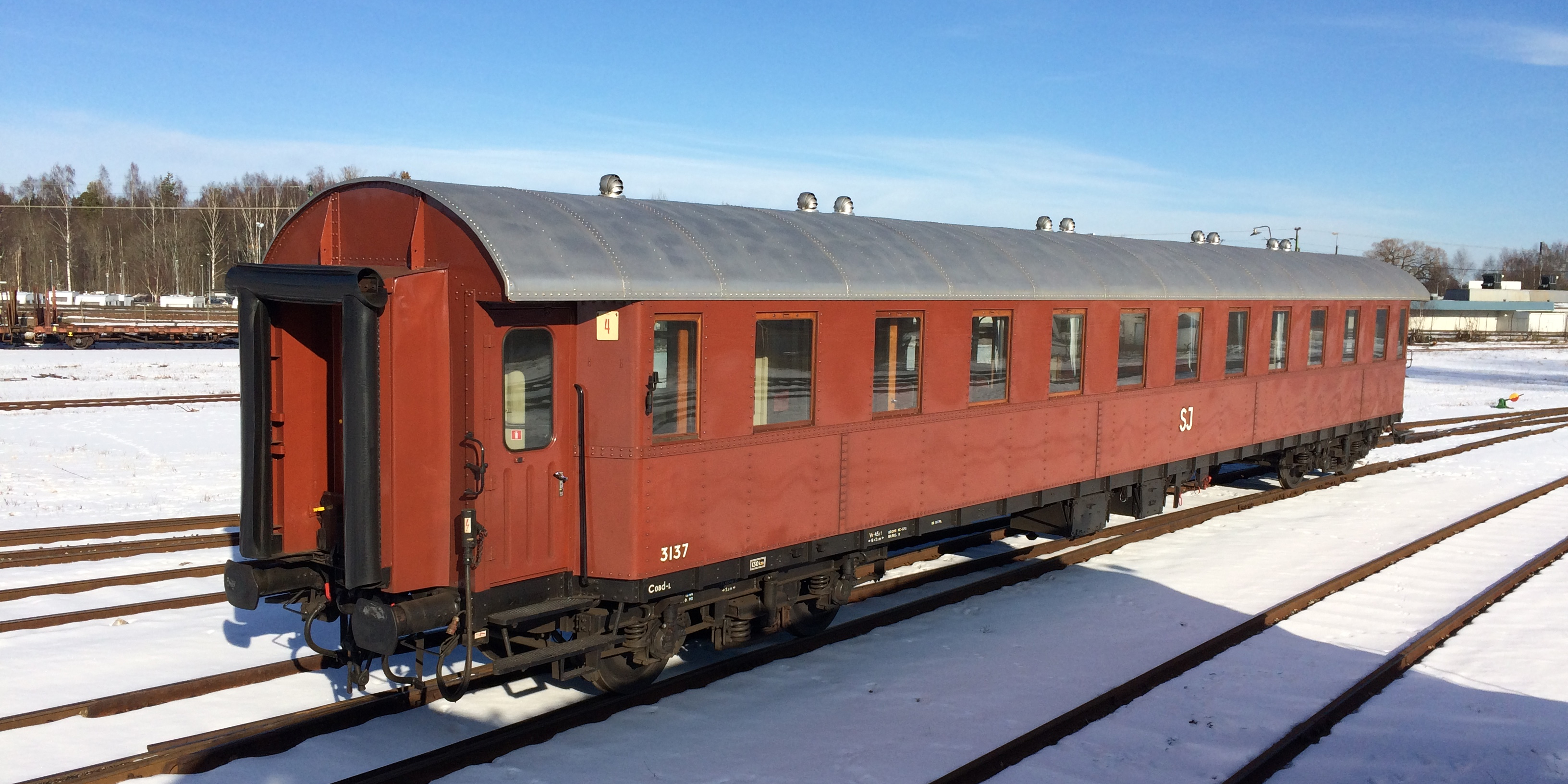 Rust red passenger car placed in the station area.